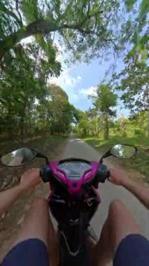 Canlı tropikal yeşilliklerle çevrili sessiz bir patika boyunca scooter sürmek, bereketli doğal ortamda huzurlu bir yolculuk yakalamak.