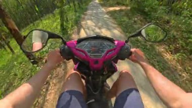 Dar bir orman yolunda mobiletle gezen bir adamın görüntüsü canlı, yemyeşil ağaçlar ve yeşilliklerle çevrili.