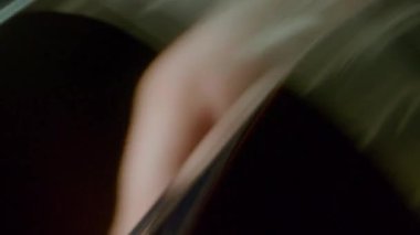 Eski bir film projektörünün yakın plan çekimi elle çalıştırılıyor, filmin makarası elle kumandayla hızla dönüyor.