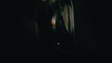 8mm 'lik film şeridi antik bir projektörün dişli mekanizmasında ilerlerken, siyaha dönmeden önce karmaşık bir hareket ve doku gösteriyor.