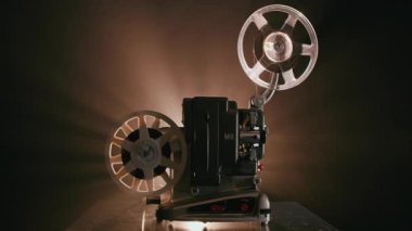 Bir retro Bolex M8 projektörü, 8 mm 'lik bir film makarası gibi çalışır, hareket halinde döner ve aksiyon halindeki klasik analog sinema ekipmanlarını gösterir.