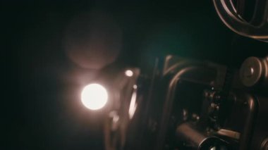 Klasik bir makara çevirme ve hareketin mekanizmadan sorunsuzca aktığı, geleneksel film projeksiyonunun nostaljik çekiciliğini yakaladığı klasik bir projektörün iş başındaki yakın çekimi.