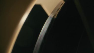 8mm 'lik bir filmin yakın çekimi, bir retro film projektörünün görüntü makarasına sıkıca yüklenmiş, aksiyon halindeki klasik sinematik teknolojiyi gözler önüne seriyor.