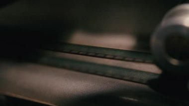 Klasik film şeridi antika bir projektörde sorunsuz çalışıyor. Sinema ışıkları film şeridi ve klasik makineler arasında yavaşça kayıyor.