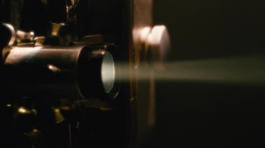 Ilık ışık yansıtan bir projeksiyonla çalışan retro film projektörünün yakın çekimi
