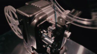 Antika Bolex M8 film projektörü, 8 mm 'lik bir film şeridini yuvarlanan bir makarada sorunsuzca oynatıyor, klasik film projeksiyonunu yakından gösteriyor.