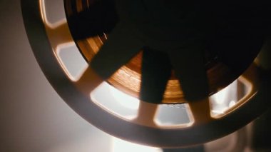 Klasik 8 mm film projektörü, film makaraya iplik geçirir. Yakın çekim vintage mekaniklerini iş başında gösterir.