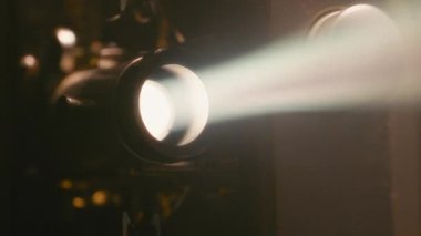 Retro projektör lenslerinin yakın çekimleri parlak parlıyor, özgün bir analog film titreşimine sahip sıcak ışık saçıyor.