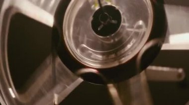 Eski bir film projektörünün yakın plan görüntüsü. 8 mm 'lik film, dönen bir Milli' den sorunsuzca geçiyor. Aksiyon sırasında eski tip sinematik ekipmanlar sergiliyor.