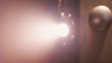 Vintage film projektörü açıldı, lensten parlayan parlak ışık nostaljik bir sinematik atmosfer yarattı.