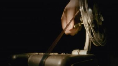 Klasik bir film projektörünü çeviren bir elin yakın çekimi dönen bir makarayla klasik bir analog sinemayı iş başında gösteriyor.