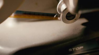 Çalışan klasik bir film projektörünün yakın çekim görüntüleri, döner top taşıyıcı mekanizması ve makinede sorunsuzca hareket eden film şeridi