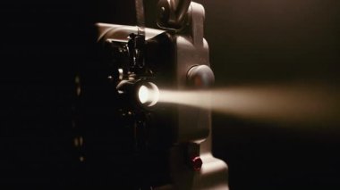Klasik bir projektör, eski moda film projeksiyonunun zamansız sihrini yakalayarak objektifinden parlak bir ışık huzmesi yayar.