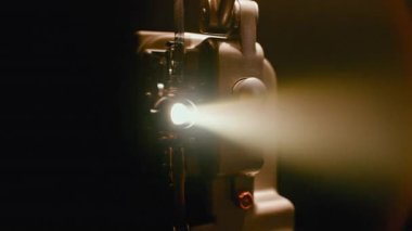 Klasik sinema projeksiyonunun nostaljik çekiciliğini yakalayan, film gösterimi sırasında ışık saçan klasik bir projektör lens.