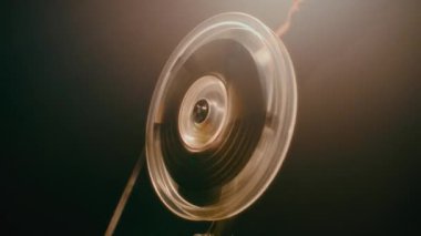 Makarayı eski bir film projektörüne elle çevirerek klasik mekanik işleyişi gösteren bir elin yakın plan çekimi.