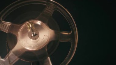 Eski bir Bolex M8 projektörünün yakın çekimi hareket halindeki bir film makarasını ve çalarken parlayan lensi gösterir