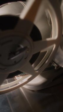Klasik bir film projektörü makarasının yakın plan çekimi, klasik mekanik detayları ve geleneksel film projeksiyonunun nostaljik çekiciliğini vurgulayarak, yavaş çekimde zarifçe dönüyor.