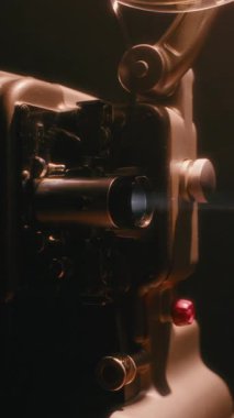 Klasik bir Bolex M8 film projektörü loş ışıkta çalışıyor, projeksiyon lensinin sıcak parıltısını hareket halinde gösteriyor