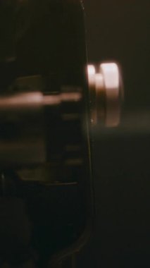 Eski bir film projektörü objektifinin arkası karanlık bir odada parlak bir ışık demeti oluşturarak nostaljik bir sinematik atmosfer yaratıyor.