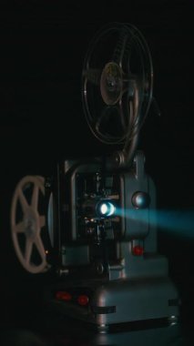 Retro Bolex M8 film projektörü parıldayan mercek ışığıyla karanlık bir odada çalışıyor ve klasik bir sinematik atmosfer yaratıyor.