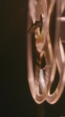 8mm 'lik film şeridi, klasik analog film ekipmanlarını hareket halinde gösteren klasik bir projektörün görüntü makarasına sorunsuzca akıyor.