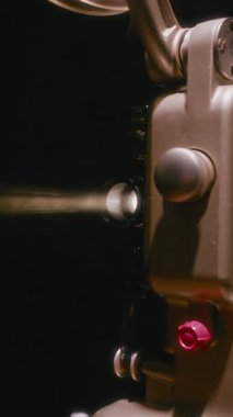 Bir Bolex M8 vintage film projektörünün objektifinden yayılan dramatik bir ışık demetini ortaya çıkarıyor.
