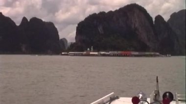 Phuket, Tayland 'daki bir tekneden alınan bu VHS görüntüleri kireçtaşı karstlarını ve uzak bir köyü beyaz korkuluklar, kırmızı ışıklar ve ekipman çerçeveleriyle yakalıyor.