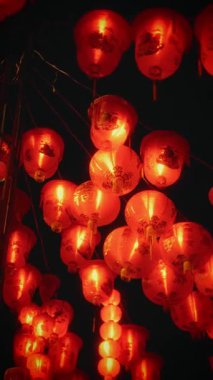 Şenlikli kırmızı fenerler gece gökyüzünün altında bir Çin Mahallesi caddesini aydınlatarak canlı ve geleneksel bir kültürel atmosfer yaratıyor.