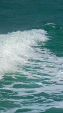 Dikey görüntüler güçlü okyanus dalgalarını yakalar ve derin deniz suyunun üzerinde beyaz köpüklere ayrılır. Doğal enerjiyi ve kıyı hareketini vurgular.