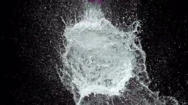 Kılıç, pembe bir su balonunu yavaş çekimde keser ve siyah bir zemine çarpıcı bir sıçrama yapar.