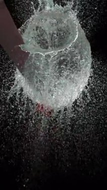 Kırmızı su balonunu kesen bir bıçağın yakın çekim çekimi dramatik patlamayı ve canlı detayları yakalıyor.