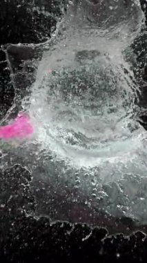 Pembe bir su balonu yavaş çekimde patlar. Bıçak içinden geçerken ayrıntılı bir sıçrama ve sıvı hareketi ortaya çıkarır.