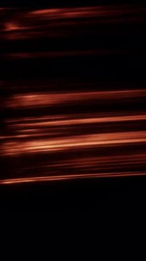 Alev benzeri çizgiler, siyah bir arkaplan üzerinde zarifçe döner. Işıldayan şekilleri, turuncu, kehribar ve altın renginde ışık yayları oluşturur.