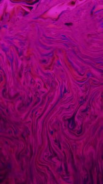 Canlı pembe ve mavi renkler bir sabun köpüğünün yüzeyinde karışıp büyüleyici, akışkan ve soyut bir desen oluşturur.