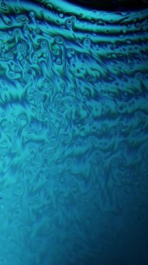 Bir sabun baloncuğunun yakın çekim görüntüsü canlı mavi eğimli girdaplar yavaşça yüzeyi boyunca hareket ediyor.