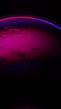 Büyüleyici pembe ve mavi bir sabun köpüğü. Koyu bir arka planda kıvrılarak rahatlatıcı ve renkli bir hareket efekti yaratıyor.