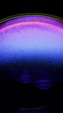 Canlı bir sabun köpüğü yüzeyi büyüleyici sıvı hareketini pembe ve mavi yanardöner renklerle gösterir.