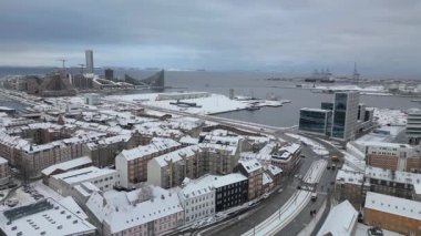 Dramatik İHA görüntüleri, kışın karla kaplı bir kıyı metropolünü, modern ve endüstriyel mimari ve dolambaçlı sokakların bir karışımını gözler önüne seriyor.