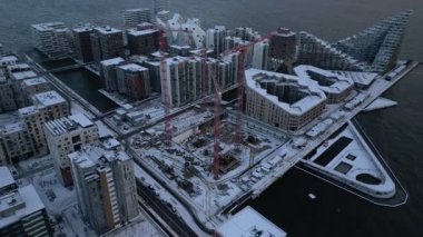 Bu hava aracı görüntüsü karla kaplı bir kıyı şehrini yakalıyor. Yükselen gökdelenler ve inşaat vinçleri sakin bir kış arka planına karşı yükseliyor.