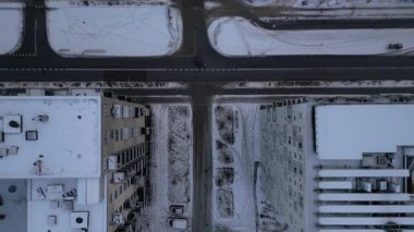 Kışın, simetrik apartmanlar, kesişen yollar, park edilmiş araçlar ve sakin kentsel manzaralı karla kaplı bir yerleşim bölgesinin genel görünümü