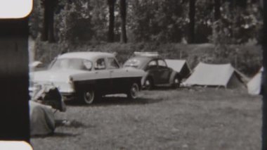 Klasik Avrupa arabaları, ormanlık bir alanda çadırların yanına park edilmiş klasik bir aile kampı anını yakalıyorlar.