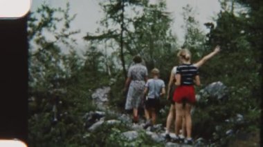 8 mm 'lik bir ailenin yemyeşil ve sakin doğal manzarayla çevrili kayalık bir göl yolu boyunca huzurlu bir yürüyüş yaptığı görüntüler.