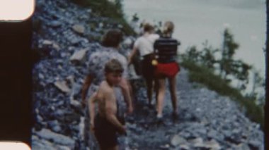 Nostaljik bir 8 mm 'lik film, İsviçre kırsalındaki kayalık göl kenarında gezen bir aileyi gösteriyor.