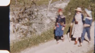 Güneşli bir günde, Kandersteg 'de nehir kenarında yürüyüş yapan bir anne ve kızının yeşil ve akan sularla çevrili olduğu 8 mm' lik bir film görüntüsü.