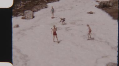 Güneşli bir günde, karla kaplı bir arazide, mutlu bir ailenin kartopu savaşının keyfini çıkarırken çekilmiş 8 mm 'lik bir film görüntüsü.