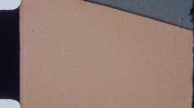 Klasik bir 8mm stop-motion animasyonunun yakın çekimi, iki dokulu yüzey arasında köşegen bir bölünme gösterir: biri sıcak, açık kahverengi tonlu ve diğeri ince kusurlu mat grisidir.