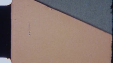 Bu 8mm stop-motion animasyon çerçevesi dinamik hareketli minimalist geometrik bir kompozisyon sergiliyor, saat yönünde bölünen bir çizgi açık kahverengi yüzeyi yavaş yavaş siliyor