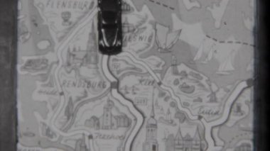 Bu klasik-ilham verici stop motion animasyon çerçevesi ayrıntılı kasaba isimleriyle süslenmiş ve ayrıntılı bir şekilde çizilmiş bir harita üzerinde hareket eden küçük bir oyuncak arabayı içerir.