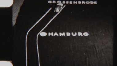 8mm 'lik stop motion animasyon çerçevesi, iki dikey beyaz çizgili, yol benzeri illüzyonu güçlendiren, karanlık bir yüzeye yerleştirilmiş minyatür oyuncak arabaları gösteriyor.