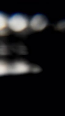 Shimmering white bokeh lights glow against a dark background, creating an elegant abstract motion backdrop